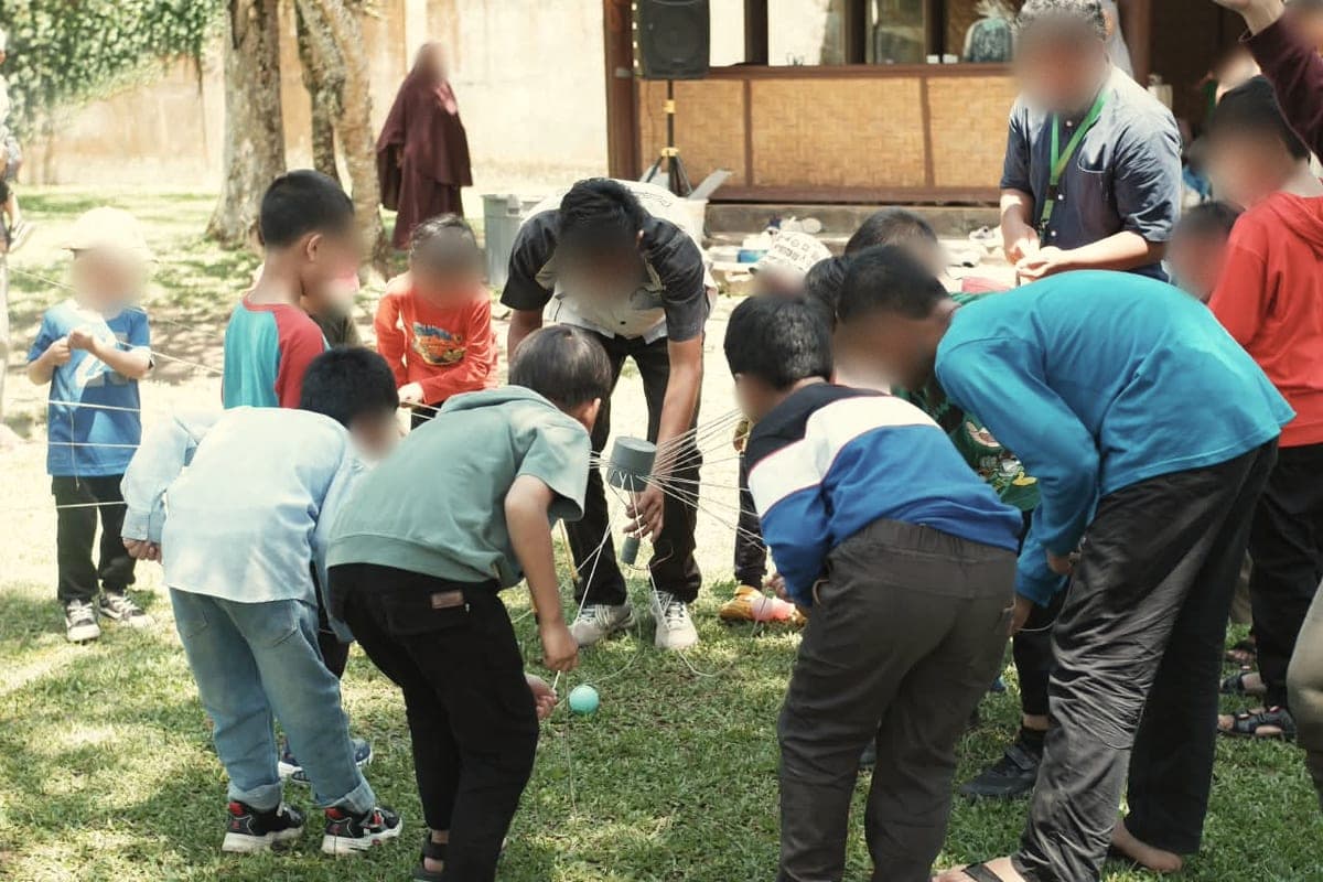 Santri bekerja sama dalam permainan tali dan gelas saat outbound
